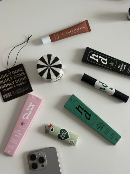Collection of cannabis products including packaging and rolling accessories on a white surface.